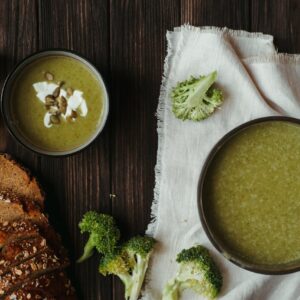 Delicious creamy broccoli soup with bread and garlic on a wooden table.