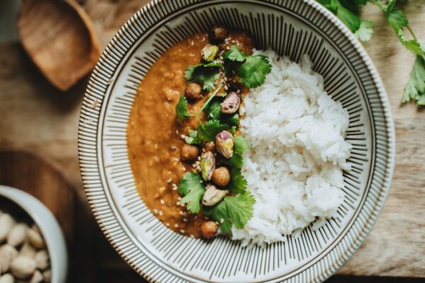 Delicious vegan rice bowl featuring lentil curry, topped with pistachios, cilantro, and sesame seeds.