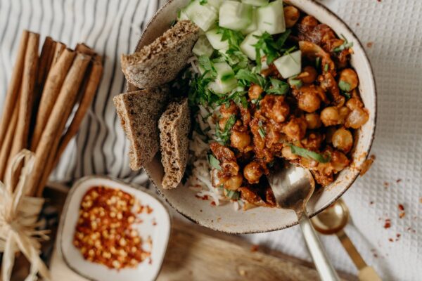 Delicious vegan bowl of chickpeas, rice, and cucumber, garnished with fresh herbs and spices.